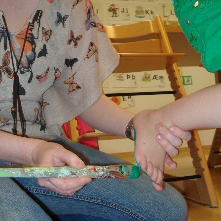 Við máluðum iljarnar okkar og settum á spjaldið framan á hurðina inn í leikskólann